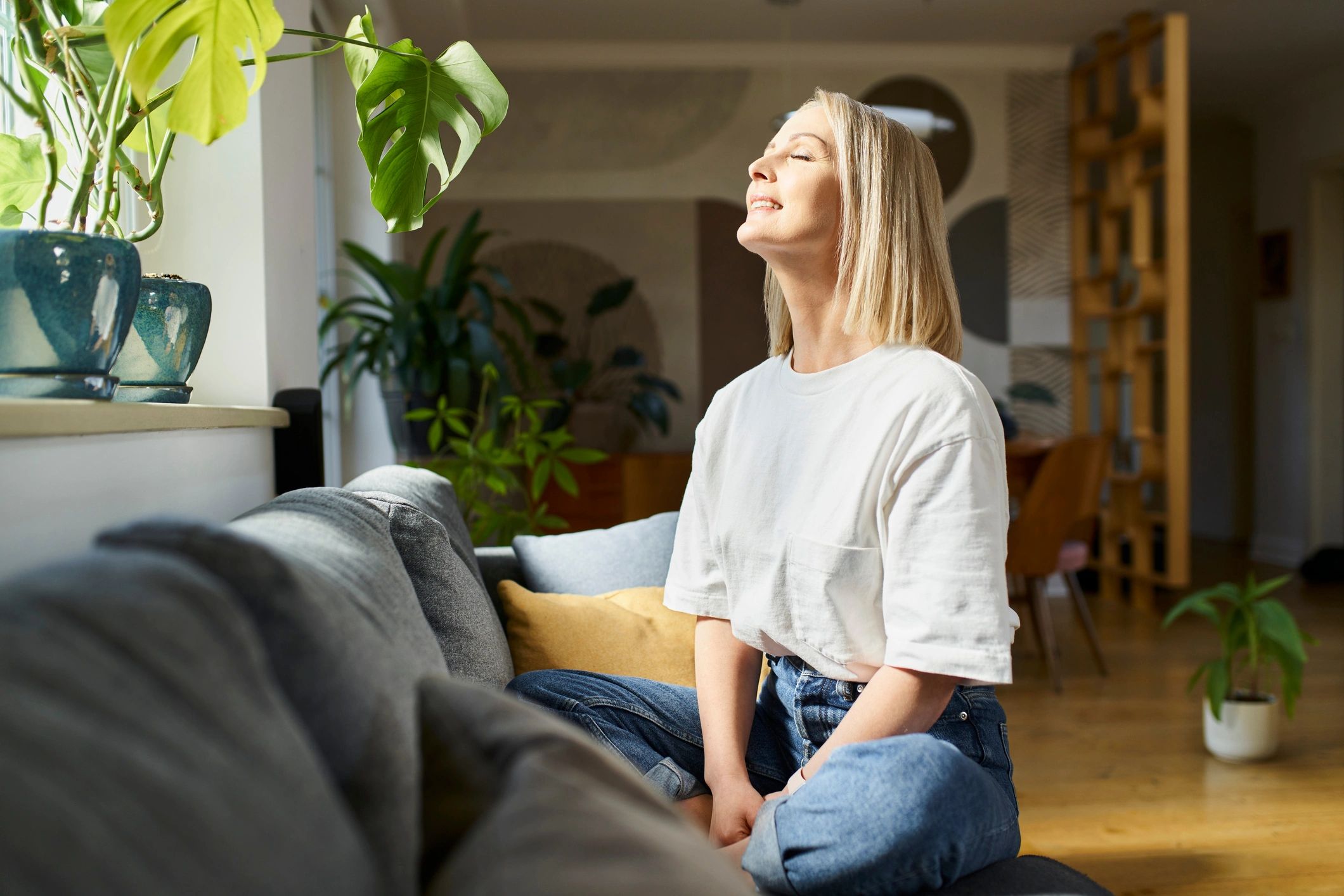 Woman sitting with eyes closed enjoying daylight at home