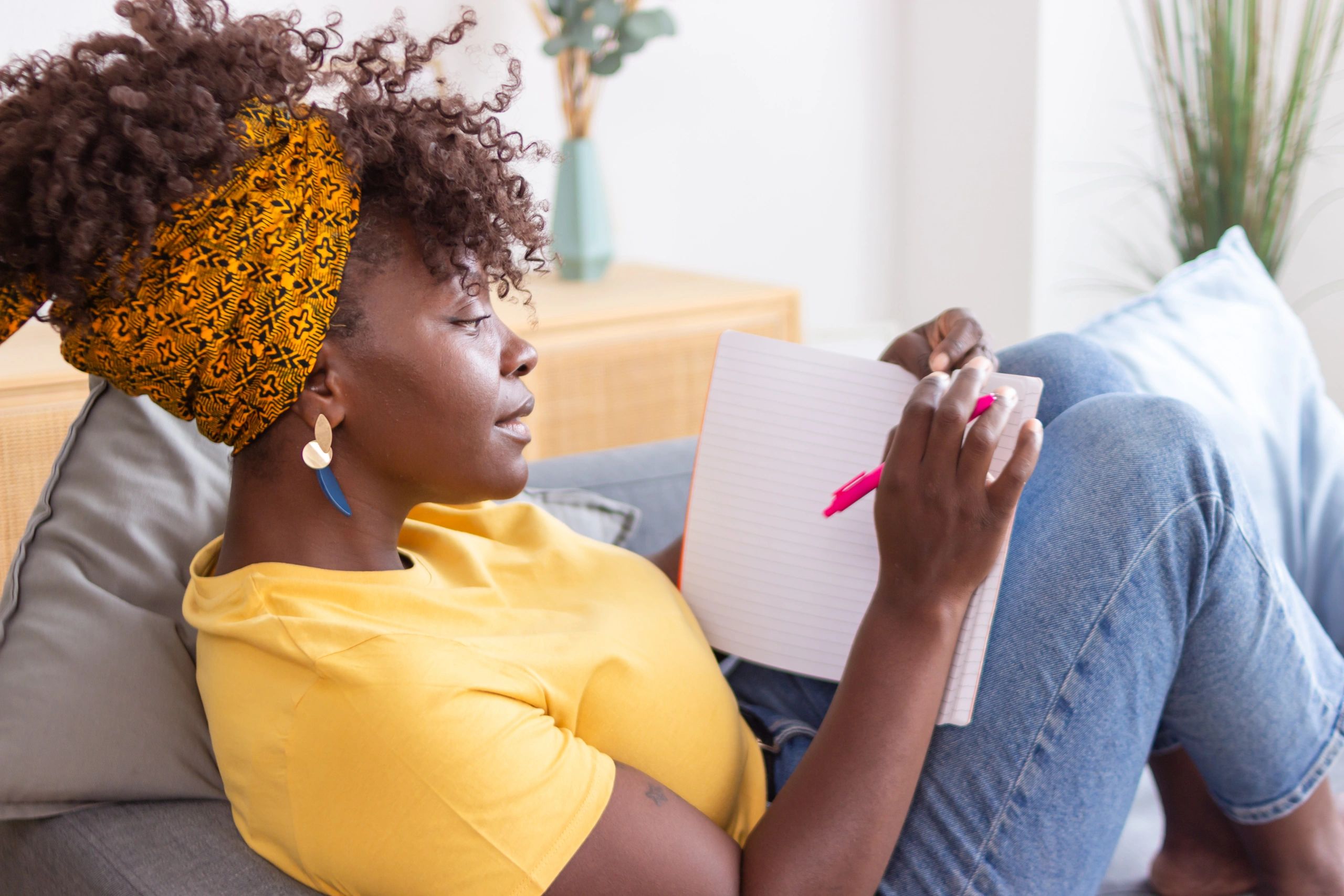 Woman writing in a notebook on a couch, receiving support and guidance
