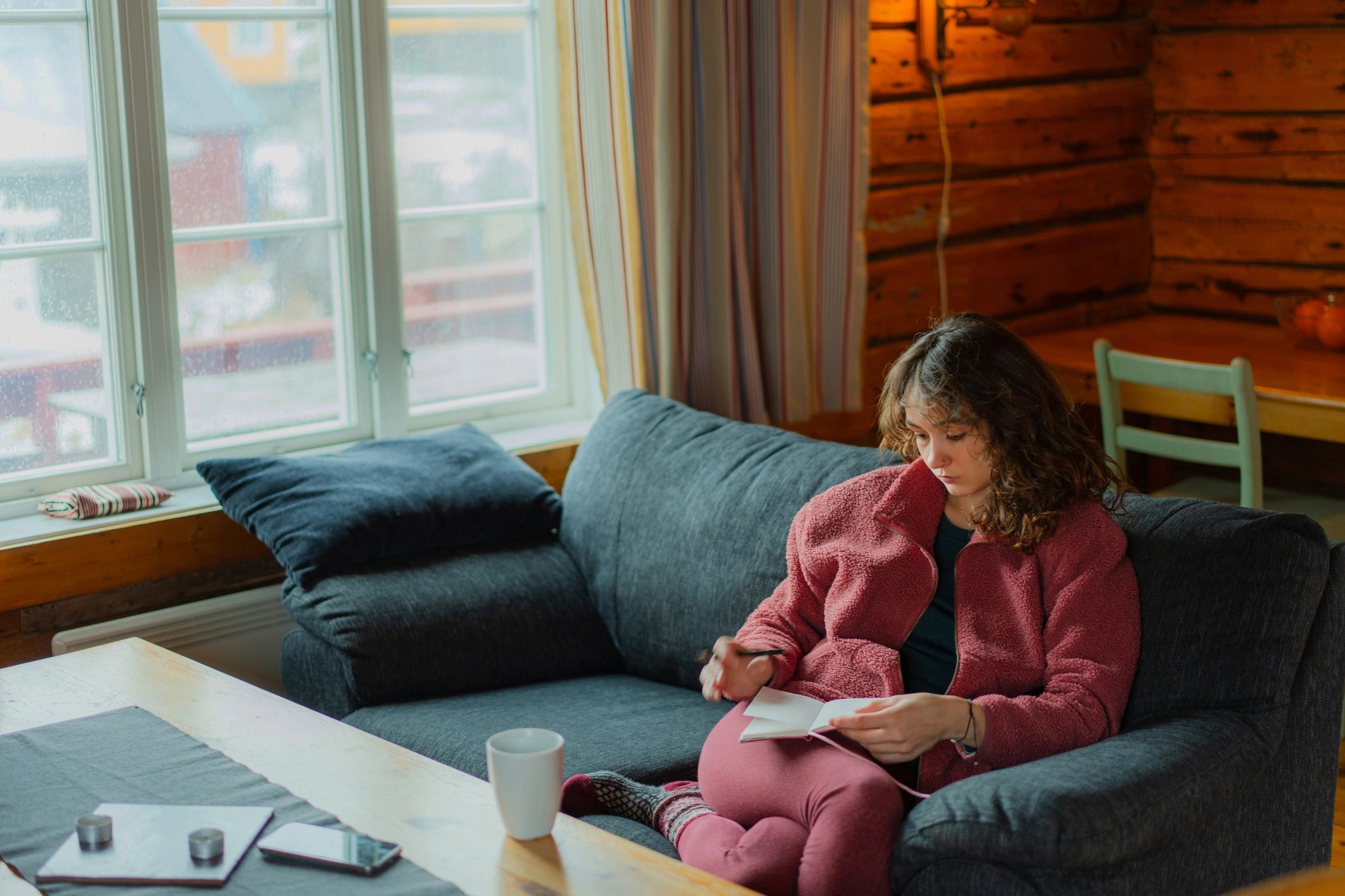Woman journaling in a cozy cabin, creating space for reflection and restoration